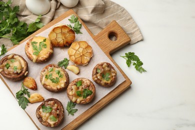 Photo of Delicious stuffed mushrooms with melted cheese, garlic and parsley on white table, flat lay