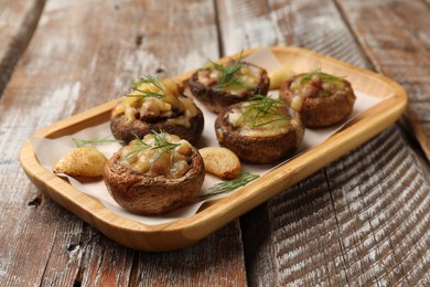 Photo of Delicious stuffed mushrooms with melted cheese, garlic and dill on color wooden table, closeup