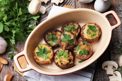 Photo of Delicious stuffed mushrooms in baking dish and products on color wooden table, flat lay