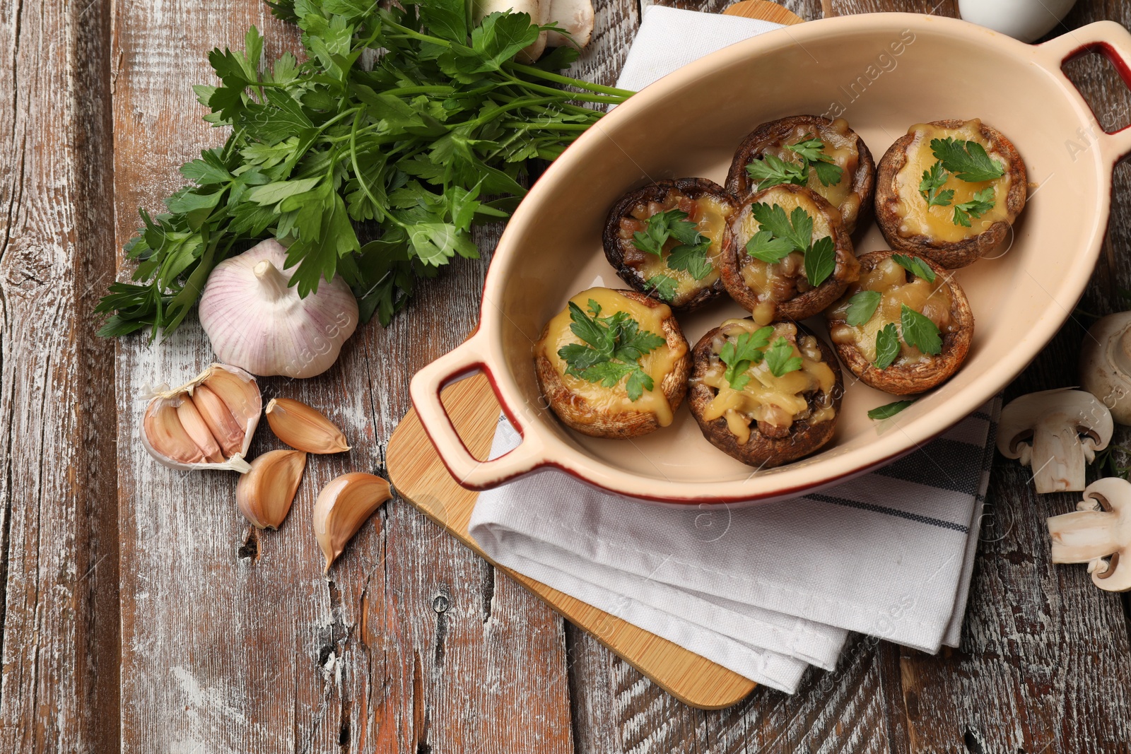 Photo of Delicious stuffed mushrooms in baking dish and products on color wooden table, flat lay