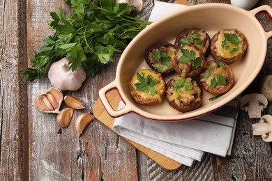 Photo of Delicious stuffed mushrooms in baking dish and products on color wooden table, flat lay