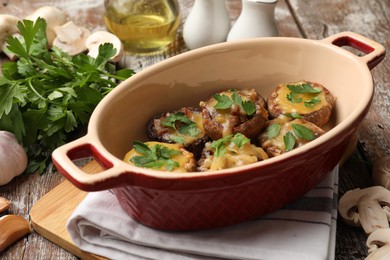 Photo of Delicious stuffed mushrooms with melted cheese and parsley in baking dish on color wooden table, closeup