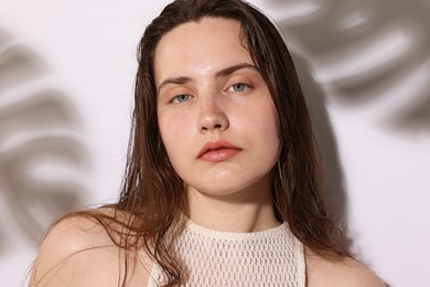 Photo of Portrait of beautiful woman with natural skin complexion on light background with shadows, closeup