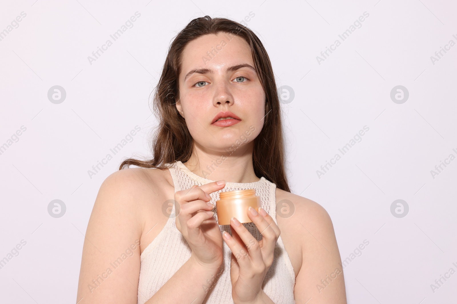 Photo of Portrait of beautiful woman with jar of skincare product on light background, closeup