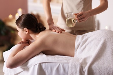 Photo of Woman receiving back massage with oil in spa salon