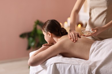 Photo of Woman receiving back massage with oil in spa salon, space for text