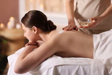 Photo of Woman receiving back massage with oil in spa salon