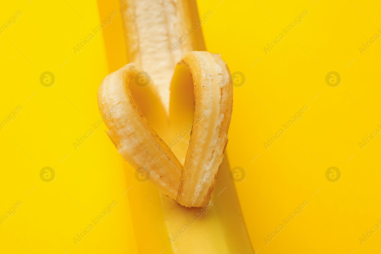 Banana with heart made of peel on yellow background, closeup Photo of Banana with heart made of peel on yellow background, closeup