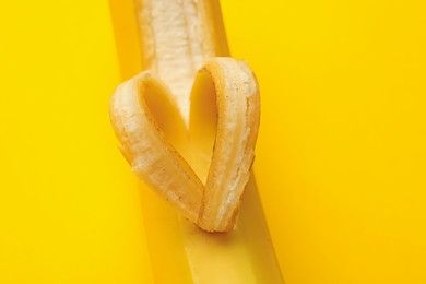 Photo of Banana with heart made of peel on yellow background, closeup