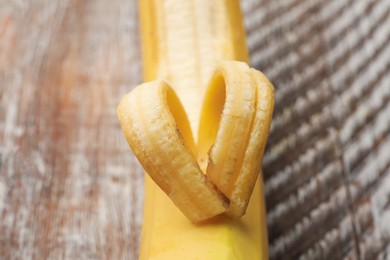 Photo of Banana with heart made of peel on wooden table, closeup