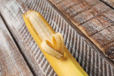 Photo of Banana with heart made of peel on wooden table, closeup