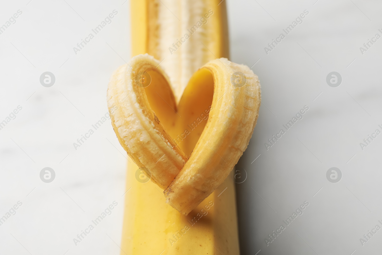 Banana with heart made of peel on white table, closeup Photo of Banana with heart made of peel on white table, closeup