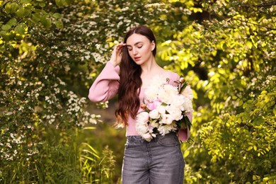 Photo of Beautiful woman with bouquet of peonies in park