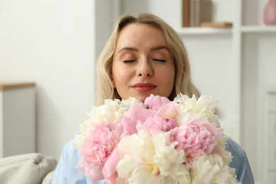 Photo of Woman with bouquet of beautiful peonies at home