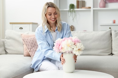 Photo of Happy woman with bouquet of beautiful peonies at home