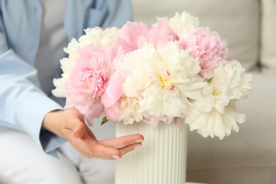 Photo of Woman with bouquet of beautiful peonies at home, closeup