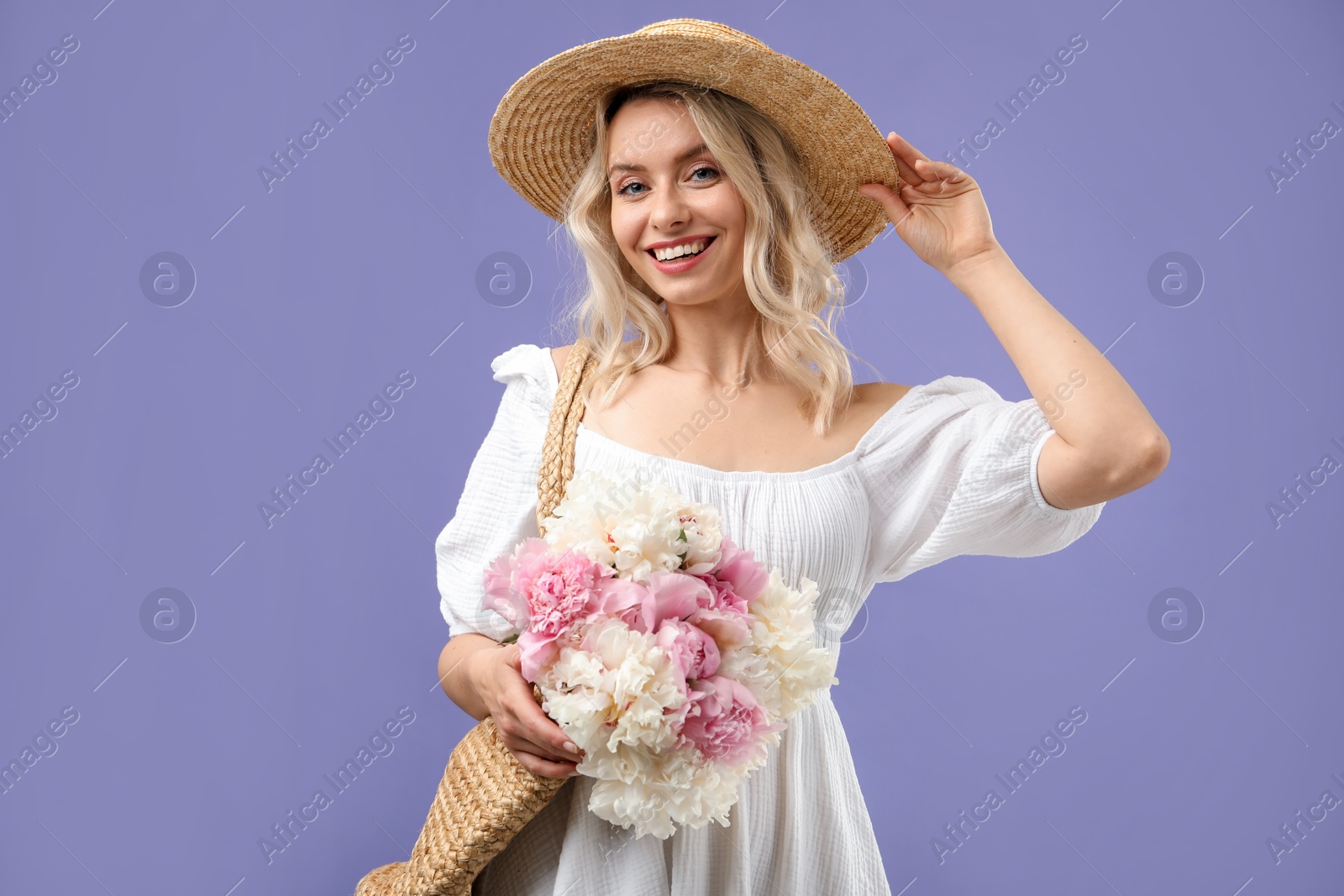 Photo of Happy woman with bouquet of beautiful peonies on purple background