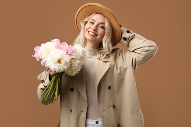 Photo of Happy woman with bouquet of beautiful peonies on brown background