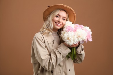Photo of Happy woman with bouquet of beautiful peonies on brown background