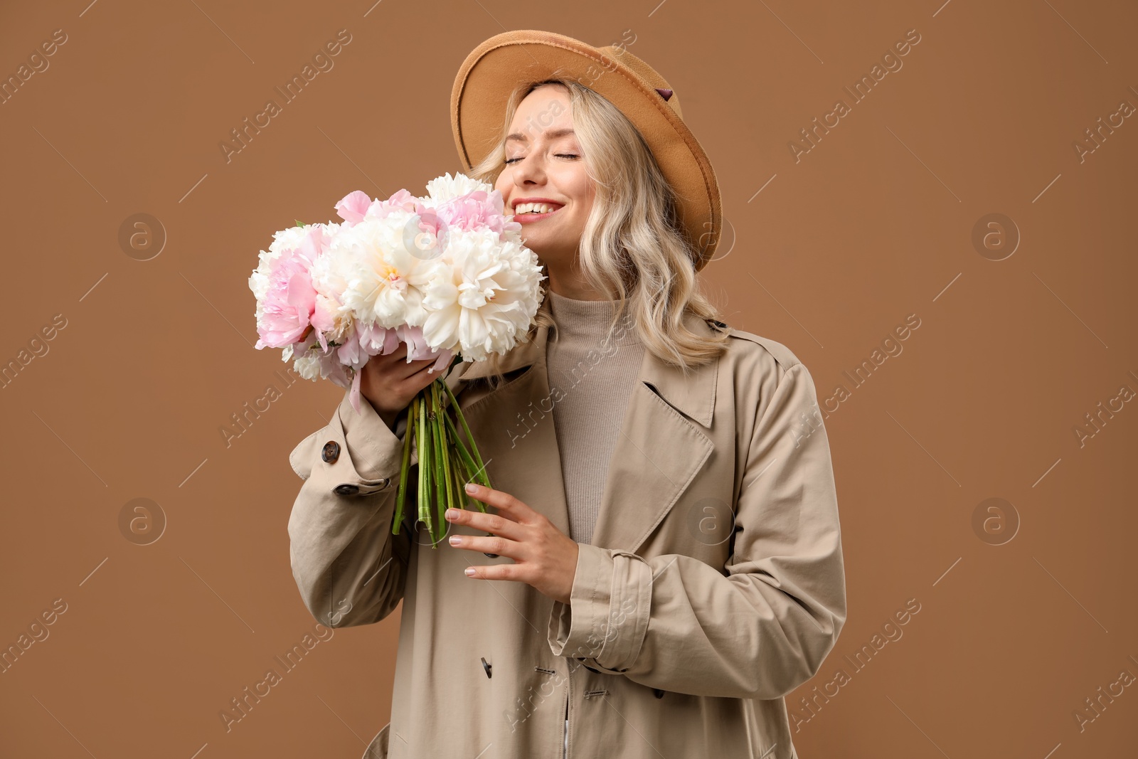 Photo of Happy woman with bouquet of beautiful peonies on brown background