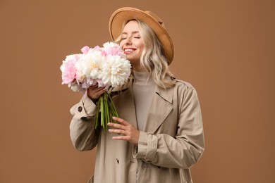 Photo of Happy woman with bouquet of beautiful peonies on brown background