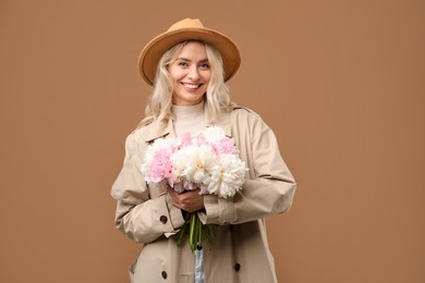 Photo of Happy woman with bouquet of beautiful peonies on brown background
