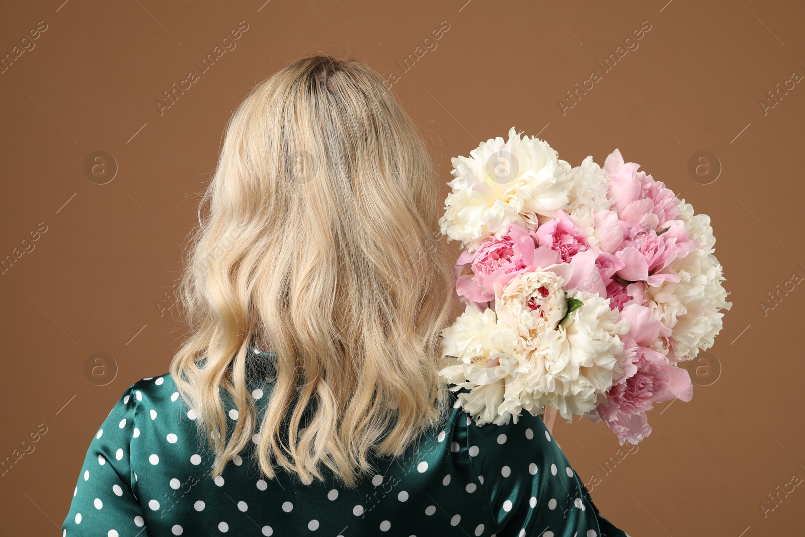 Photo of Woman with bouquet of beautiful peonies on brown background, back view