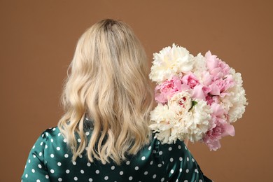 Photo of Woman with bouquet of beautiful peonies on brown background, back view