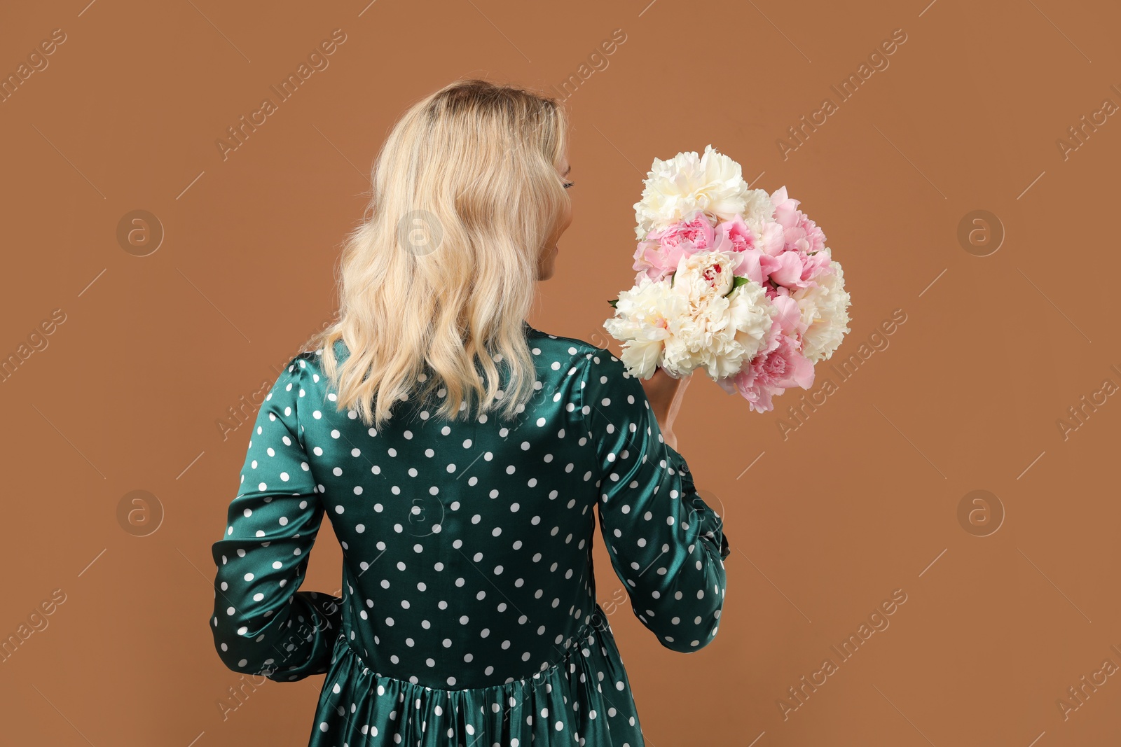 Photo of Woman with bouquet of beautiful peonies on brown background