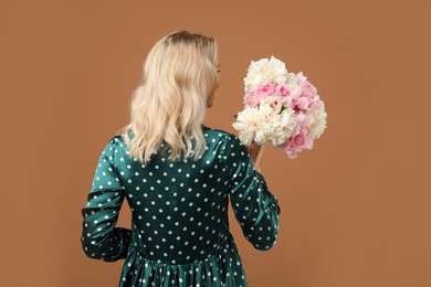 Photo of Woman with bouquet of beautiful peonies on brown background