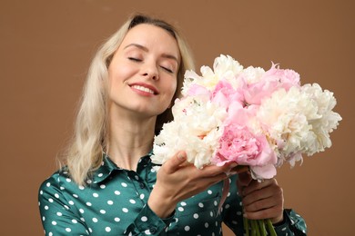 Photo of Happy woman with bouquet of beautiful peonies on brown background