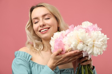 Photo of Happy woman with bouquet of beautiful peonies on pink background