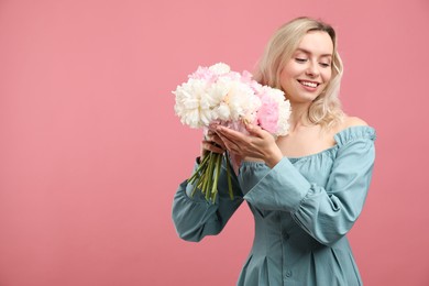 Photo of Happy woman with bouquet of beautiful peonies on pink background, space for text