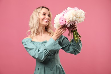 Photo of Happy woman with bouquet of beautiful peonies on pink background