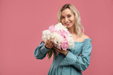 Photo of Happy woman with bouquet of beautiful peonies on pink background, space for text