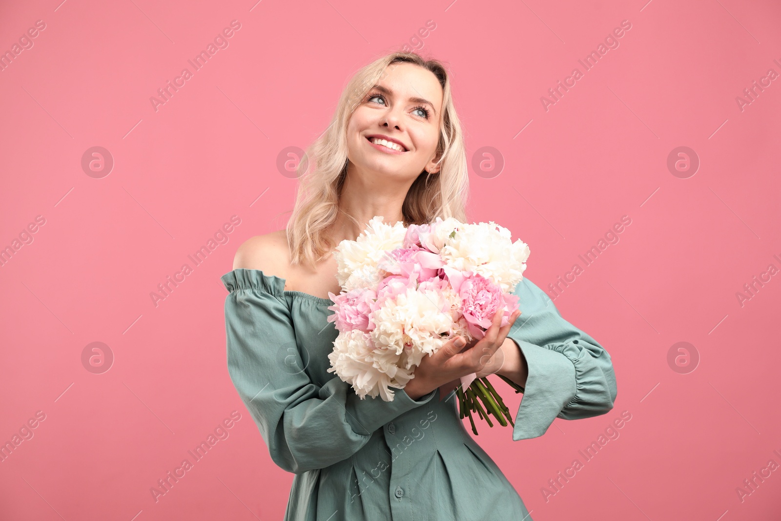 Photo of Happy woman with bouquet of beautiful peonies on pink background