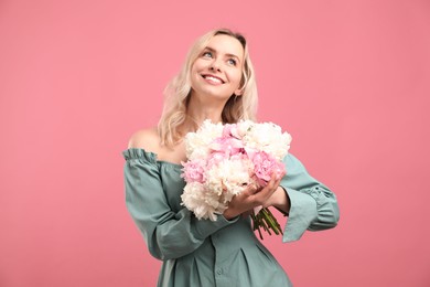 Photo of Happy woman with bouquet of beautiful peonies on pink background