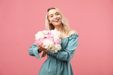 Photo of Happy woman with bouquet of beautiful peonies on pink background