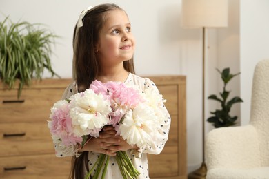 Photo of Cute little girl with bouquet of beautiful peonies at home, space for text