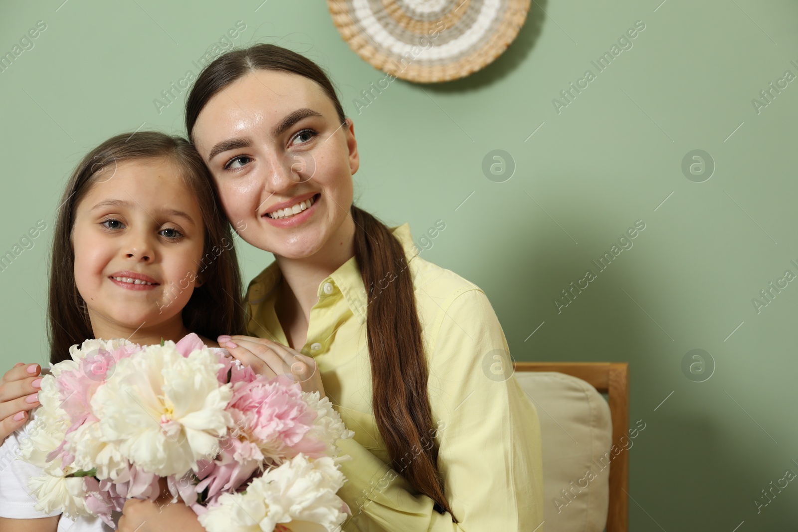 Mother and her daughter with bouquet of beautiful peonies at home Photo of Mother and her daughter with bouquet of beautiful peonies at home