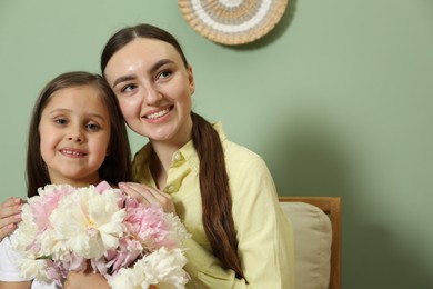 Photo of Mother and her daughter with bouquet of beautiful peonies at home
