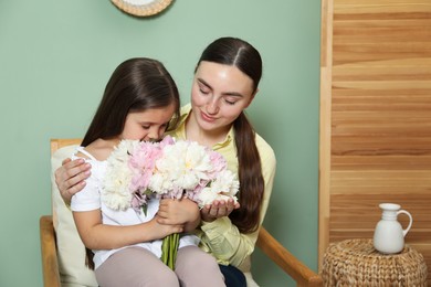 Photo of Mother and her daughter with bouquet of beautiful peonies at home