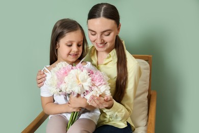 Photo of Mother and her daughter with bouquet of beautiful peonies at home