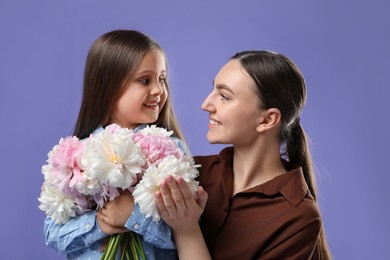Photo of Mother and her daughter with bouquet of beautiful peonies on purple background