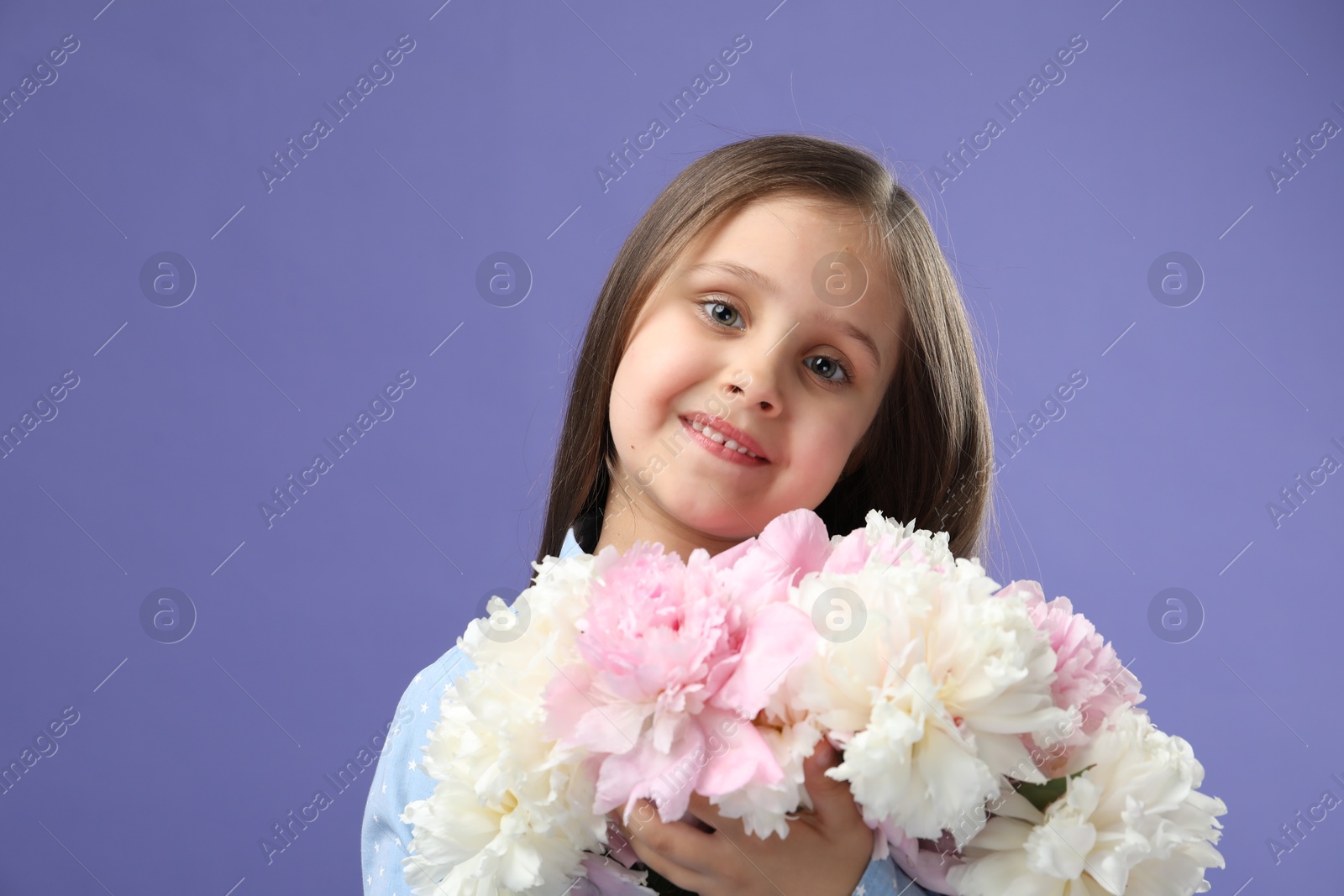 Photo of Cute little girl with bouquet of beautiful peonies on purple background, space for text