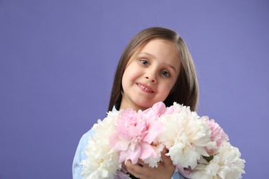 Photo of Cute little girl with bouquet of beautiful peonies on purple background, space for text