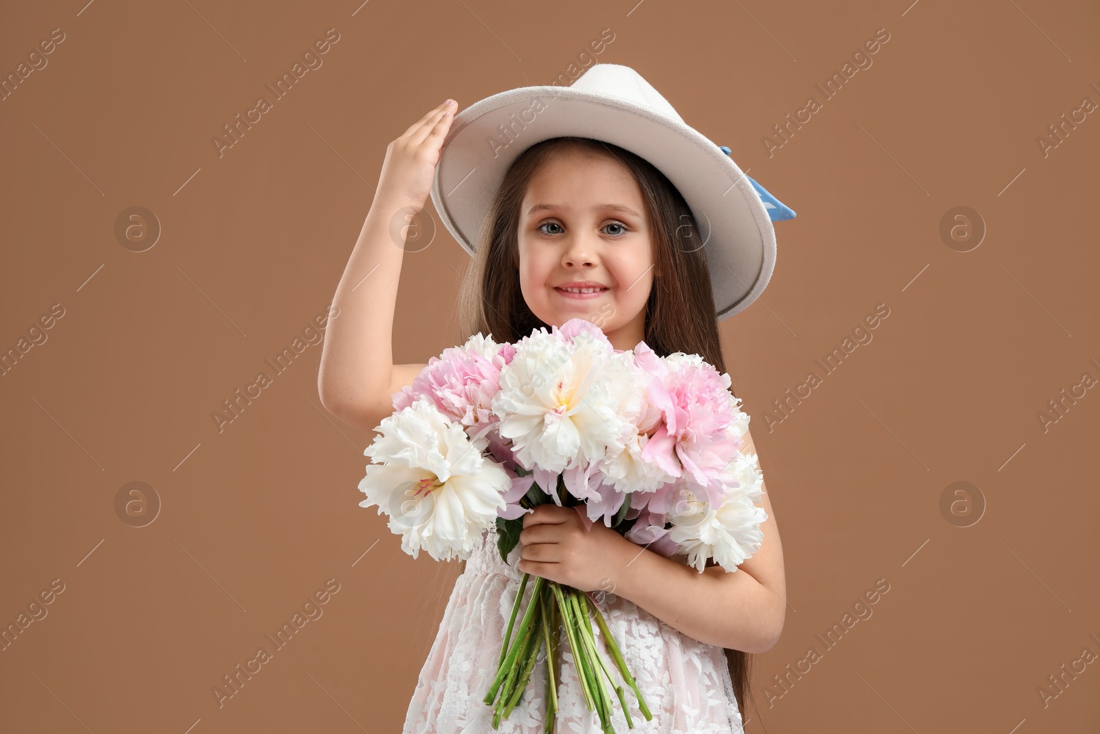 Photo of Cute little girl with bouquet of beautiful peonies on brown background