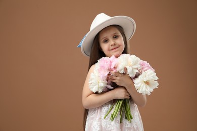 Photo of Cute little girl with bouquet of beautiful peonies on brown background, space for text