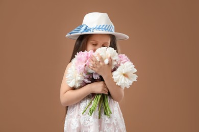 Photo of Cute little girl with bouquet of beautiful peonies on brown background