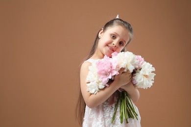 Photo of Cute little girl with bouquet of beautiful peonies on brown background, space for text